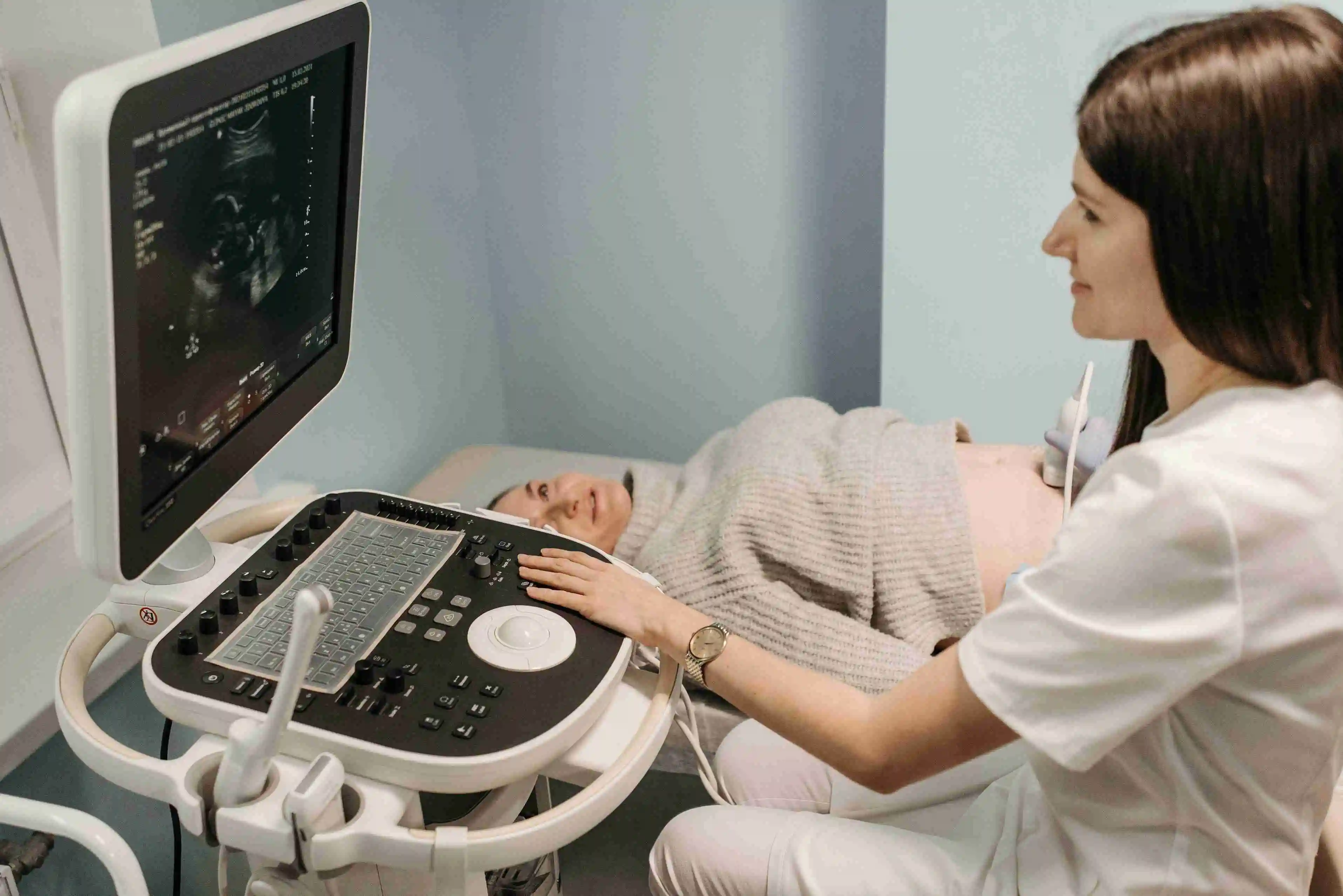 Doctor performing third trimester prenatal checkup and monitoring fetal heart rate